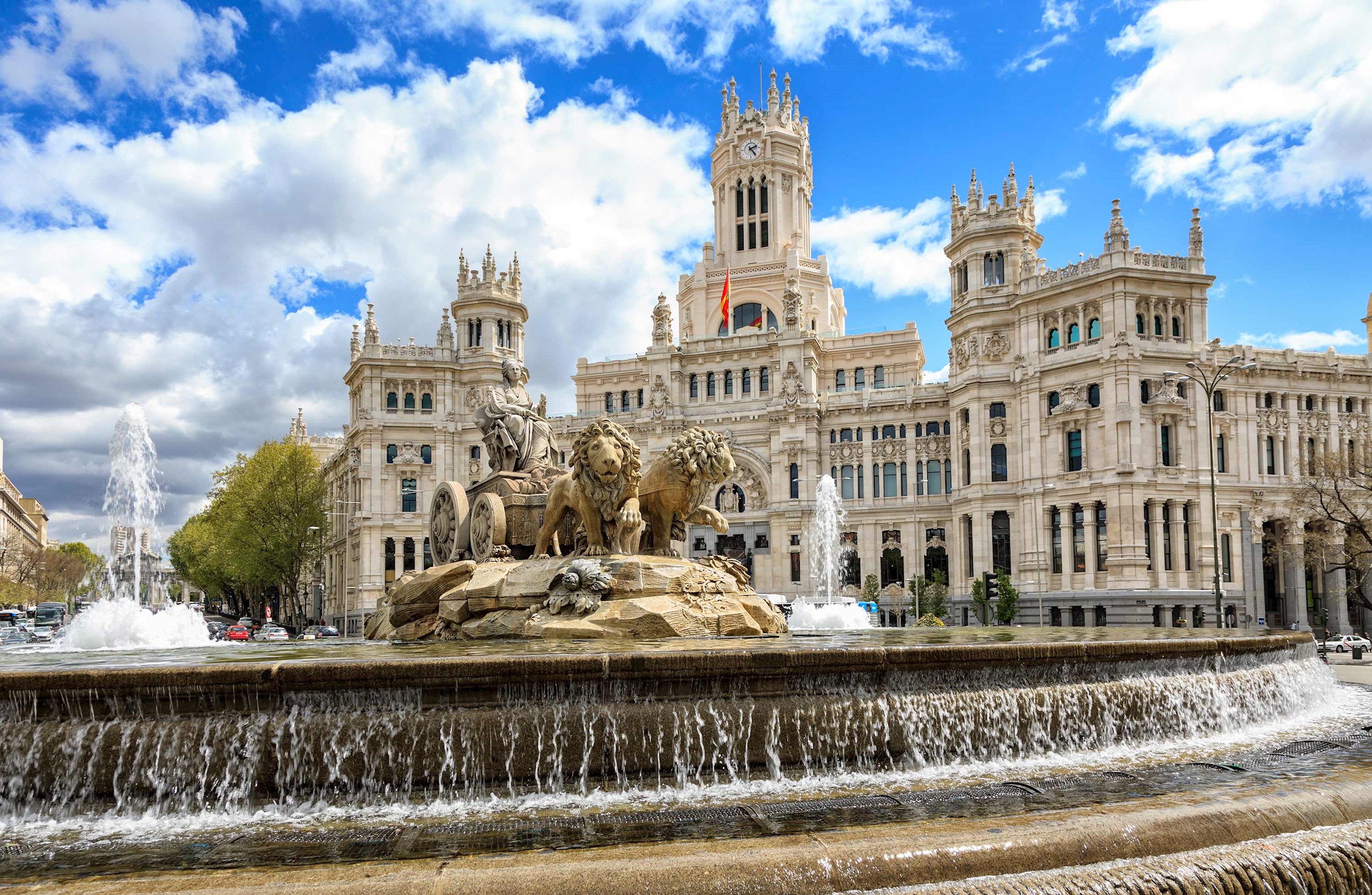 Large fountain with lion statues in front of grand building in Madrid, Spain