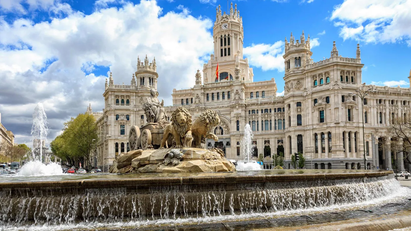 Large fountain with lion statues in front of grand building in Madrid, Spain