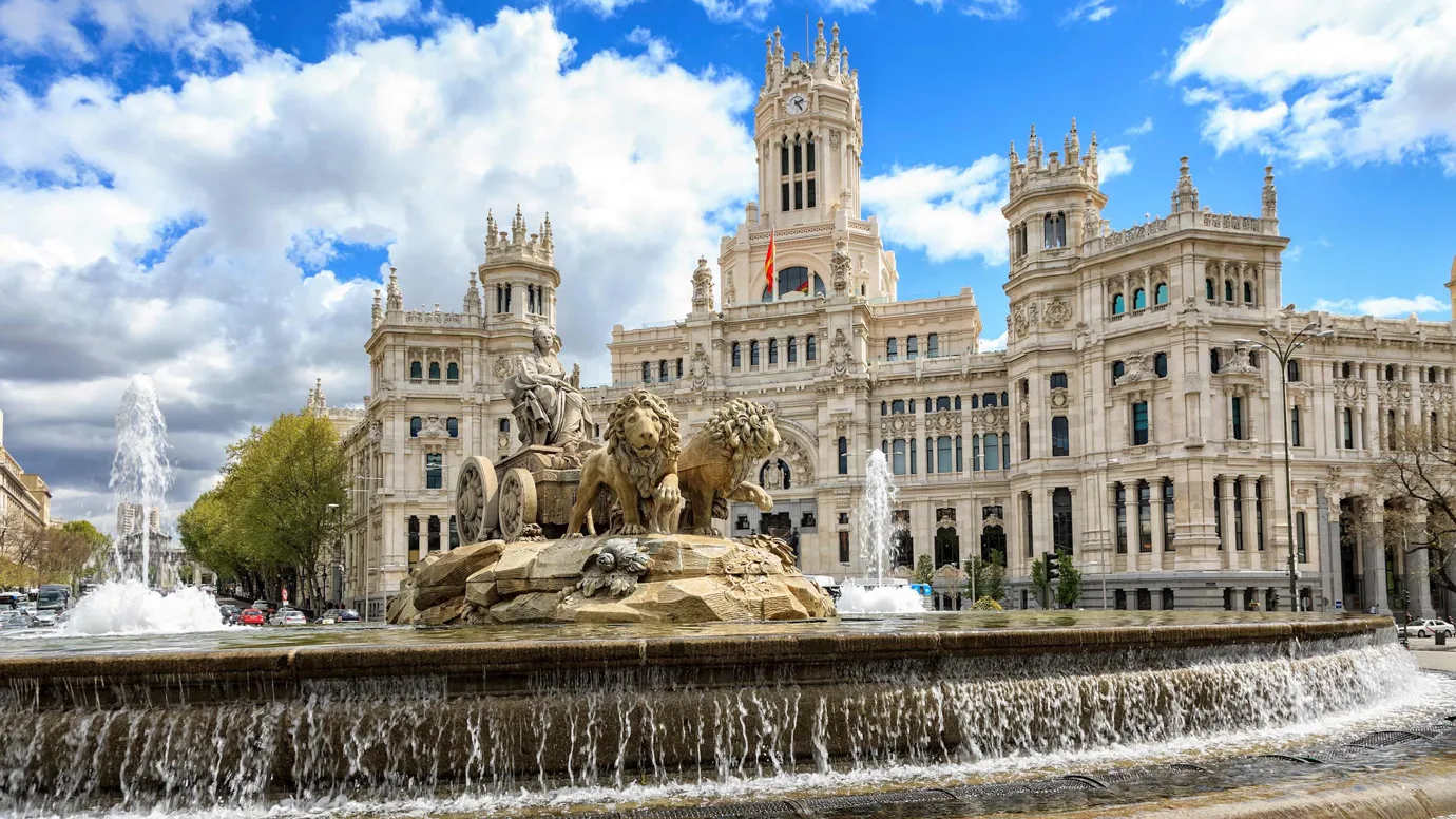 Large fountain with lion statues in front of grand building in Madrid, Spain