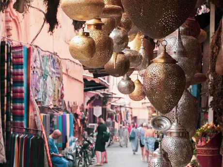 A narrow alleyway in a market in Cairo, Egypt, full of stalls selling fabrics and decorative lamps.