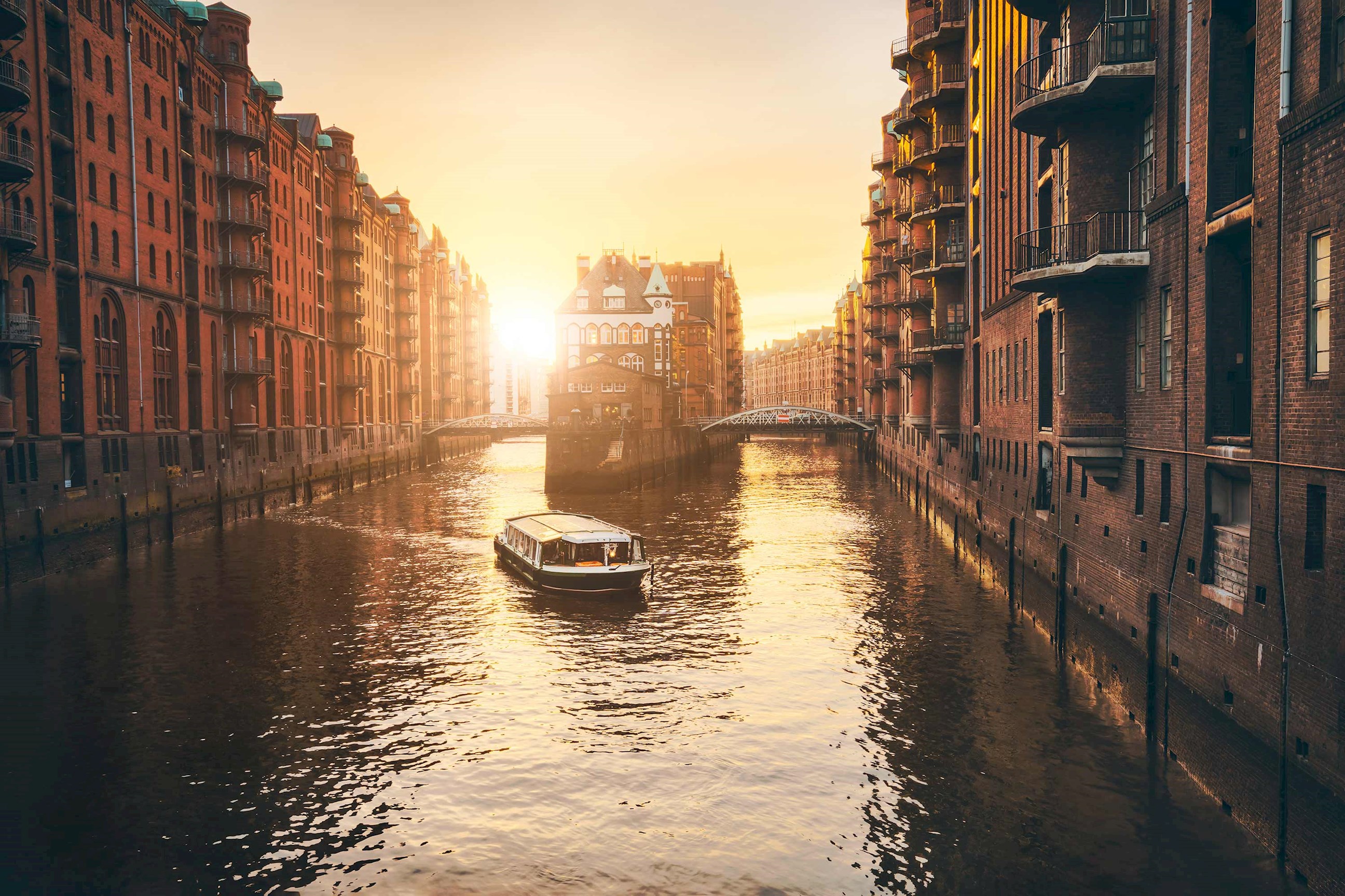Hamburg Speicherstadt canal with boat and red-brick buildings at sunset