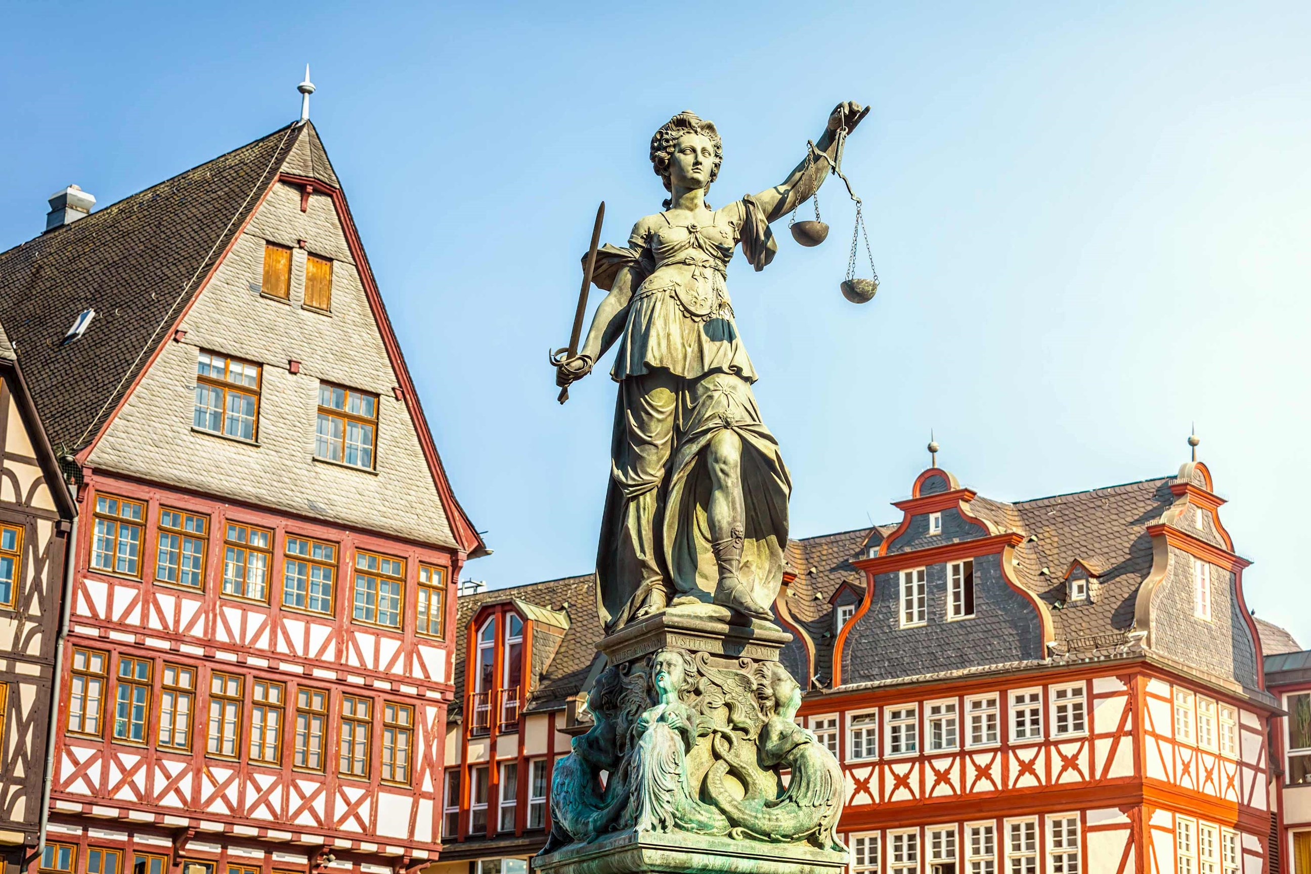 Statue of Lady Justice stands among traditional buildings in Frankfurt, Germany