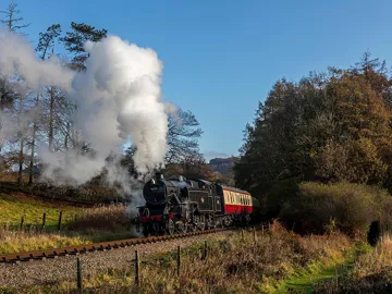 Steam train crossing countryside with autumn trees in England