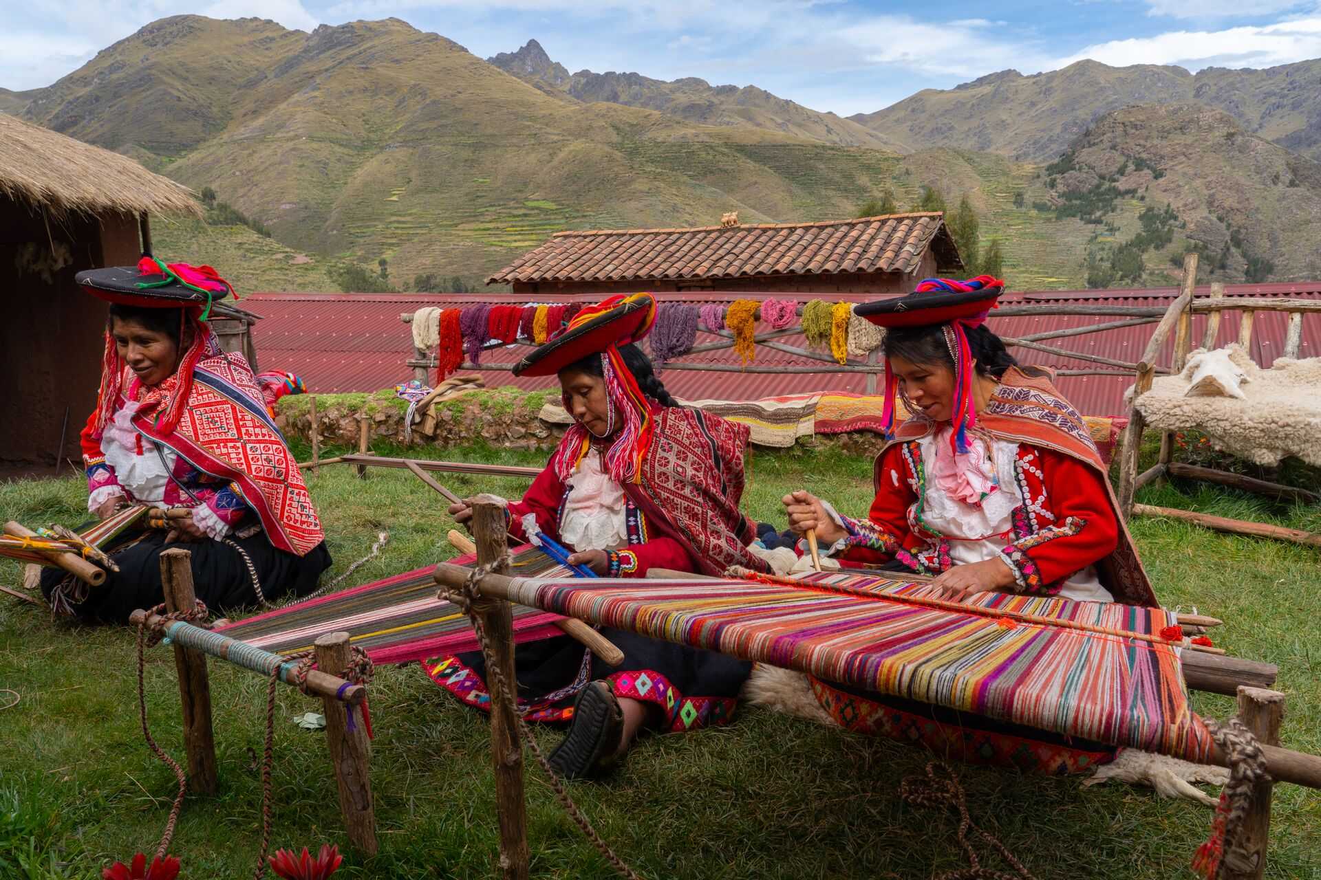 Three local weavers in colourful traditional dress in Peru