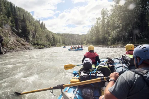 A group of people riding on the back of a raft down a river