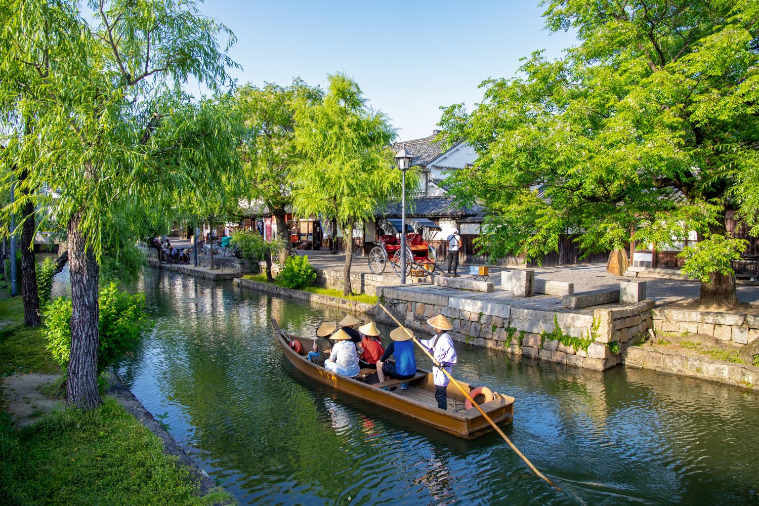 People wearing traditional Japanese hats on a boat on Canal Kurashiki Japan