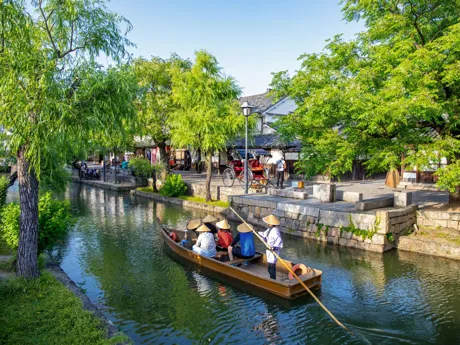 People wearing traditional Japanese hats on a boat on Canal Kurashiki Japan