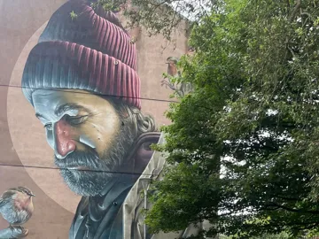 Large painting on building wall near greenery in Glasgow, Scotland