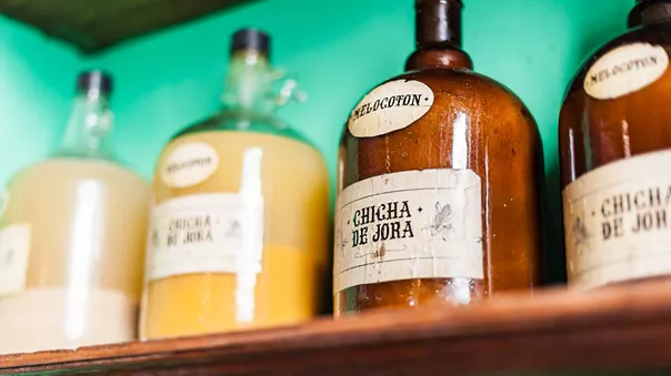 A shelf filled with bottles of liquid Chicha De Jora