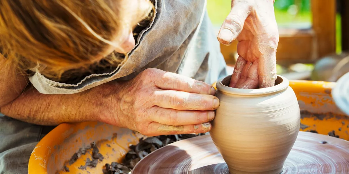 A Woman Potter Working Clay On A Potters Wheel In Her Workshop