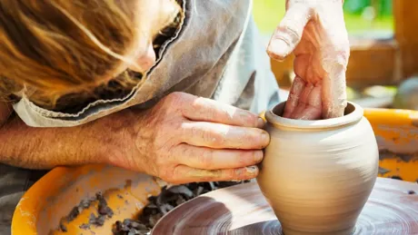 A Woman Potter Working Clay On A Potters Wheel In Her Workshop