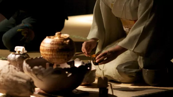 A person sitting on the floor with a bowl and a vase during Tea Ceremony in Kyoto Japan