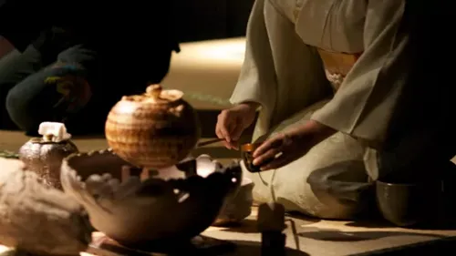 A person sitting on the floor with a bowl and a vase during Tea Ceremony in Kyoto Japan