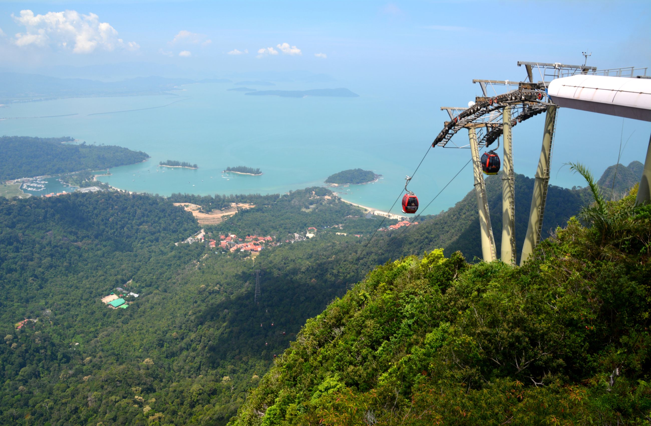 The Langkawi cable car in Malaysia descends a lush green mountainside toward the coast and beaches beyond.