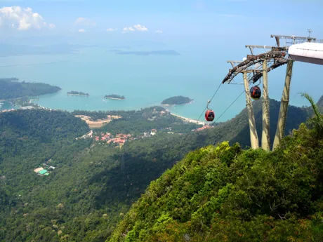 The Langkawi cable car in Malaysia descends a lush green mountainside toward the coast and beaches beyond.
