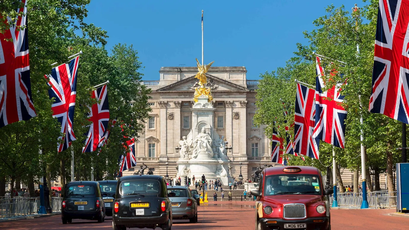 Buckingham Palace with Union Jack Flags and taxis in London, England