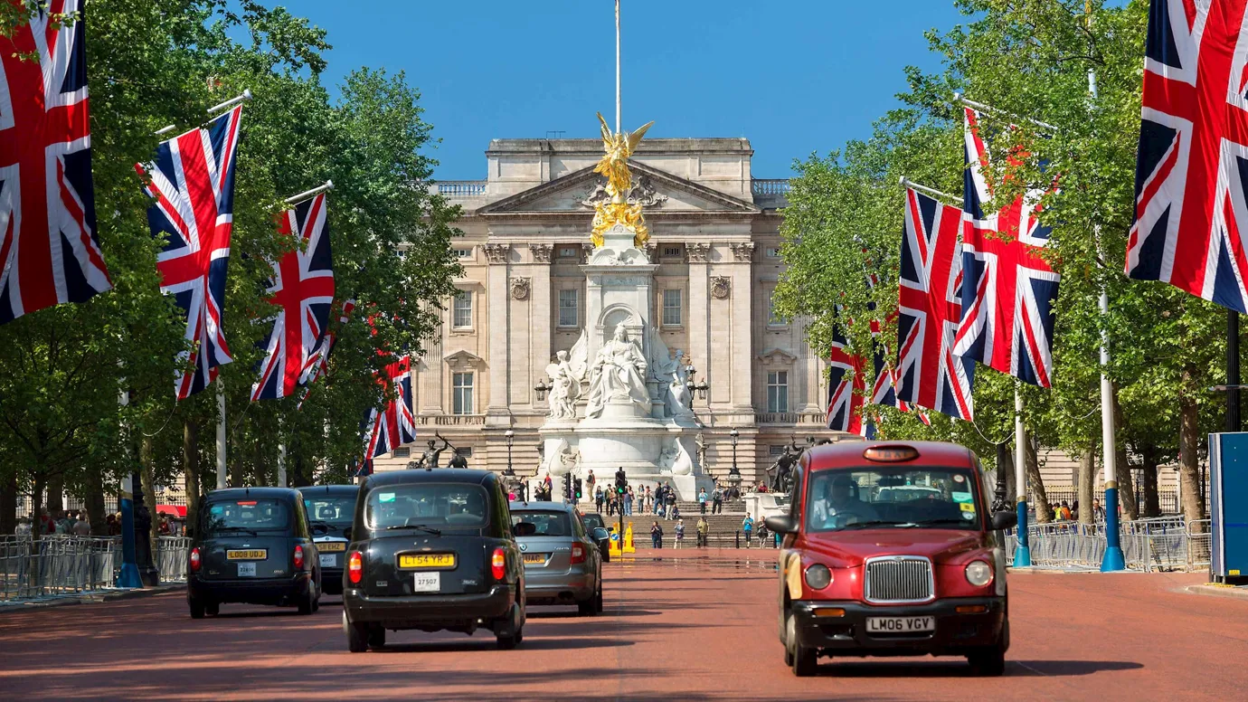 Buckingham Palace with Union Jack Flags and taxis in London, England