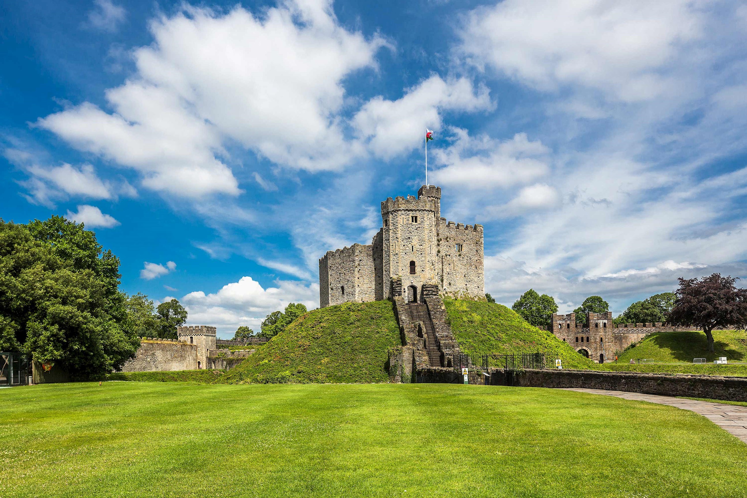 Cardiff Castle keep on grassy mound under blue sky with clouds in Wales
