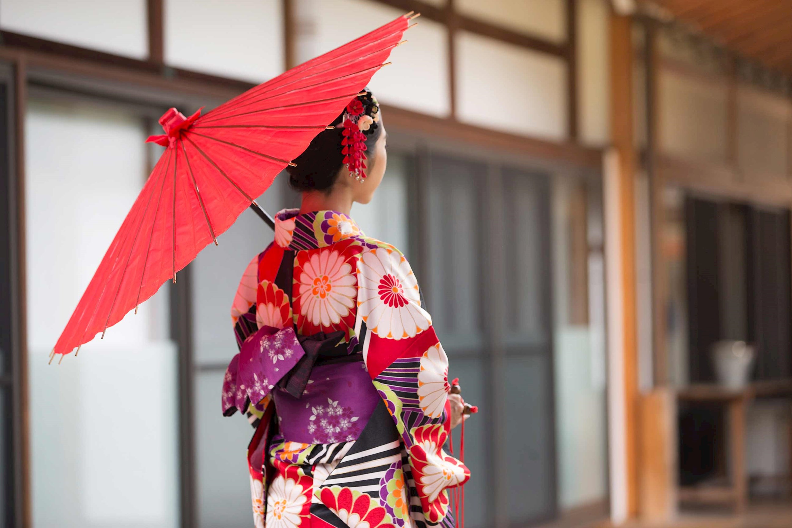 Person wearing colourful floral kimono holding red traditional Japanese umbrella