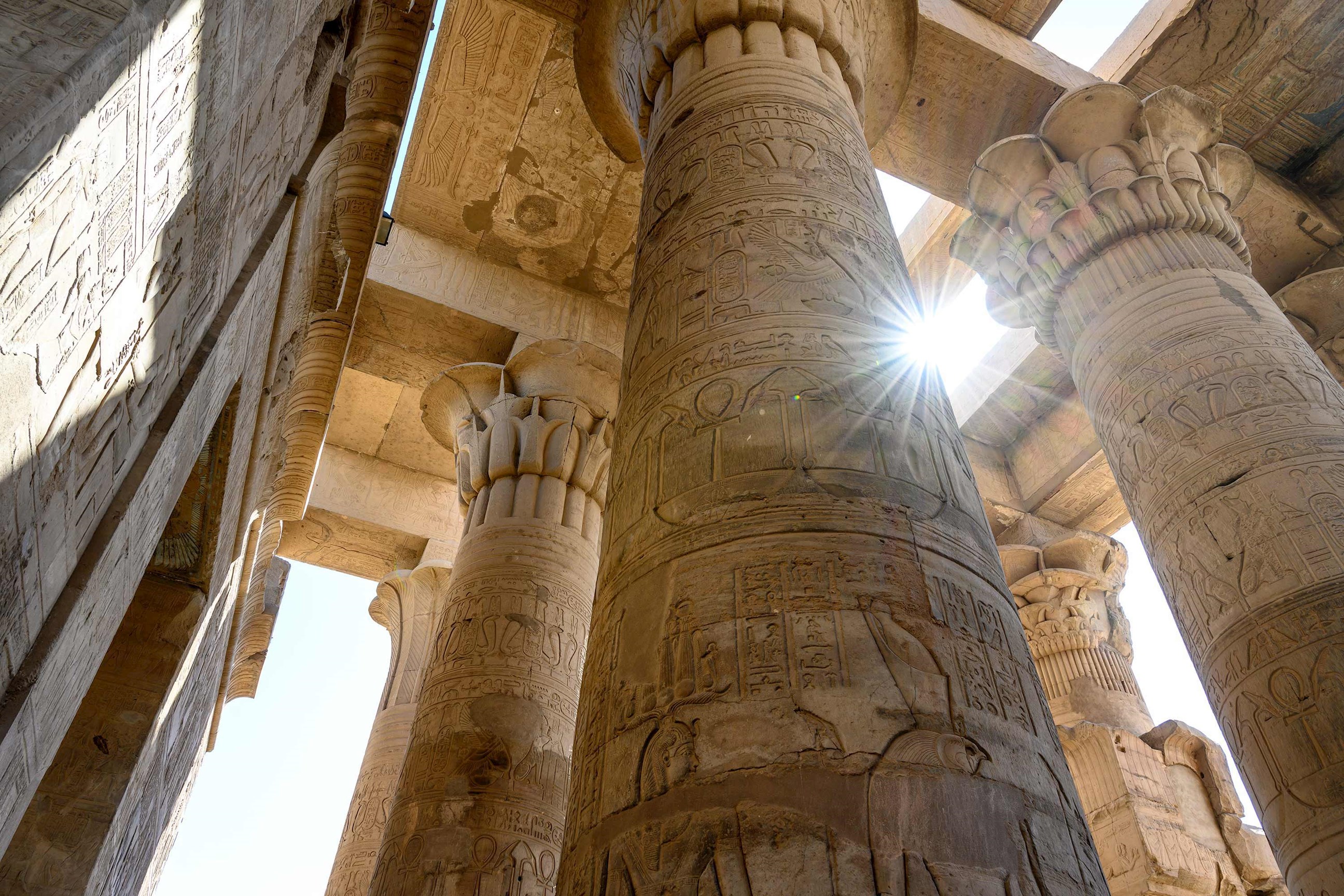 Sun glaring through ancient carved buildings in Kom Ombo, Egypt