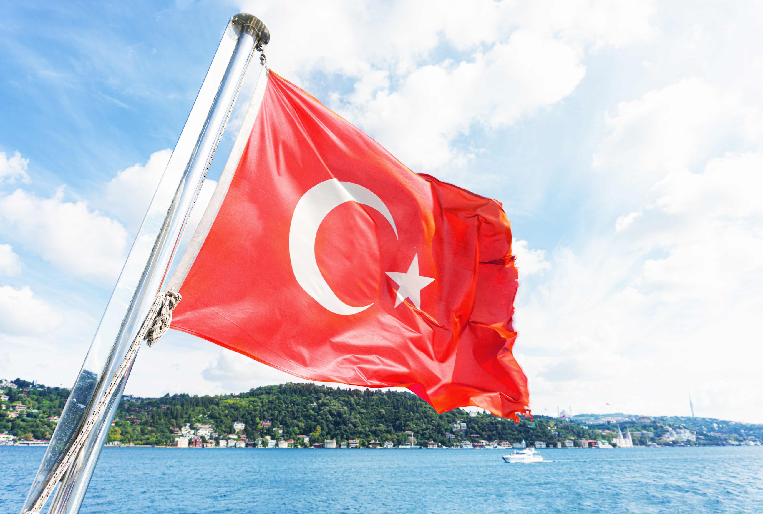 Turkish flag waving on boat with sea and hills background