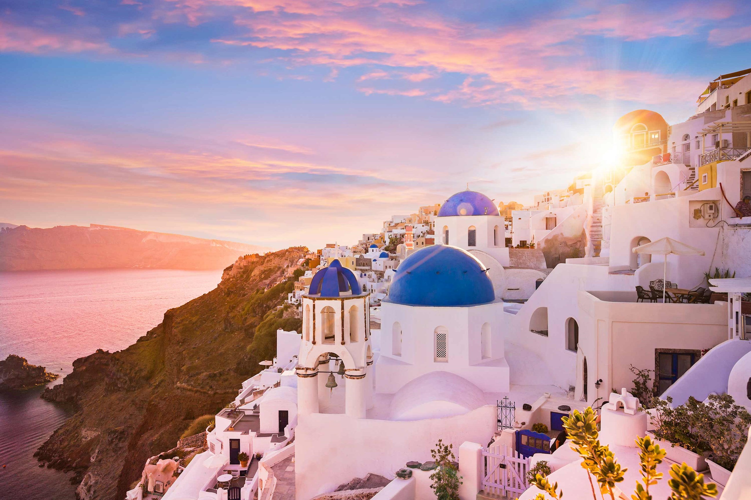 Sunset over whitewashed buildings and blue-domed churches in Santorini, Greece