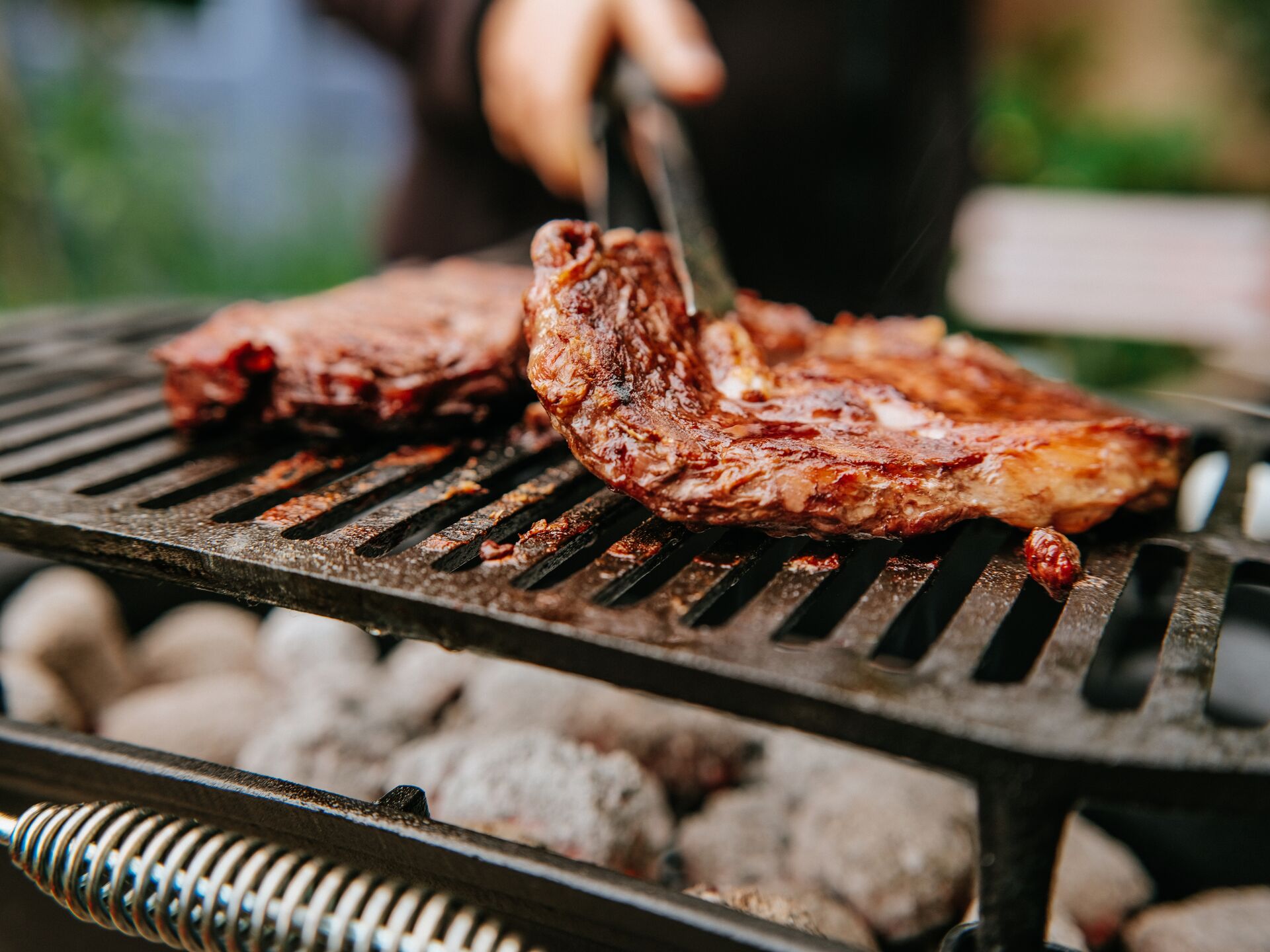 Traveller cooking BBQ steaks on a flame grill