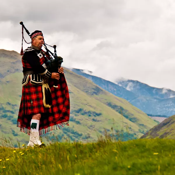 Scottish bagpiper playing in the highlands