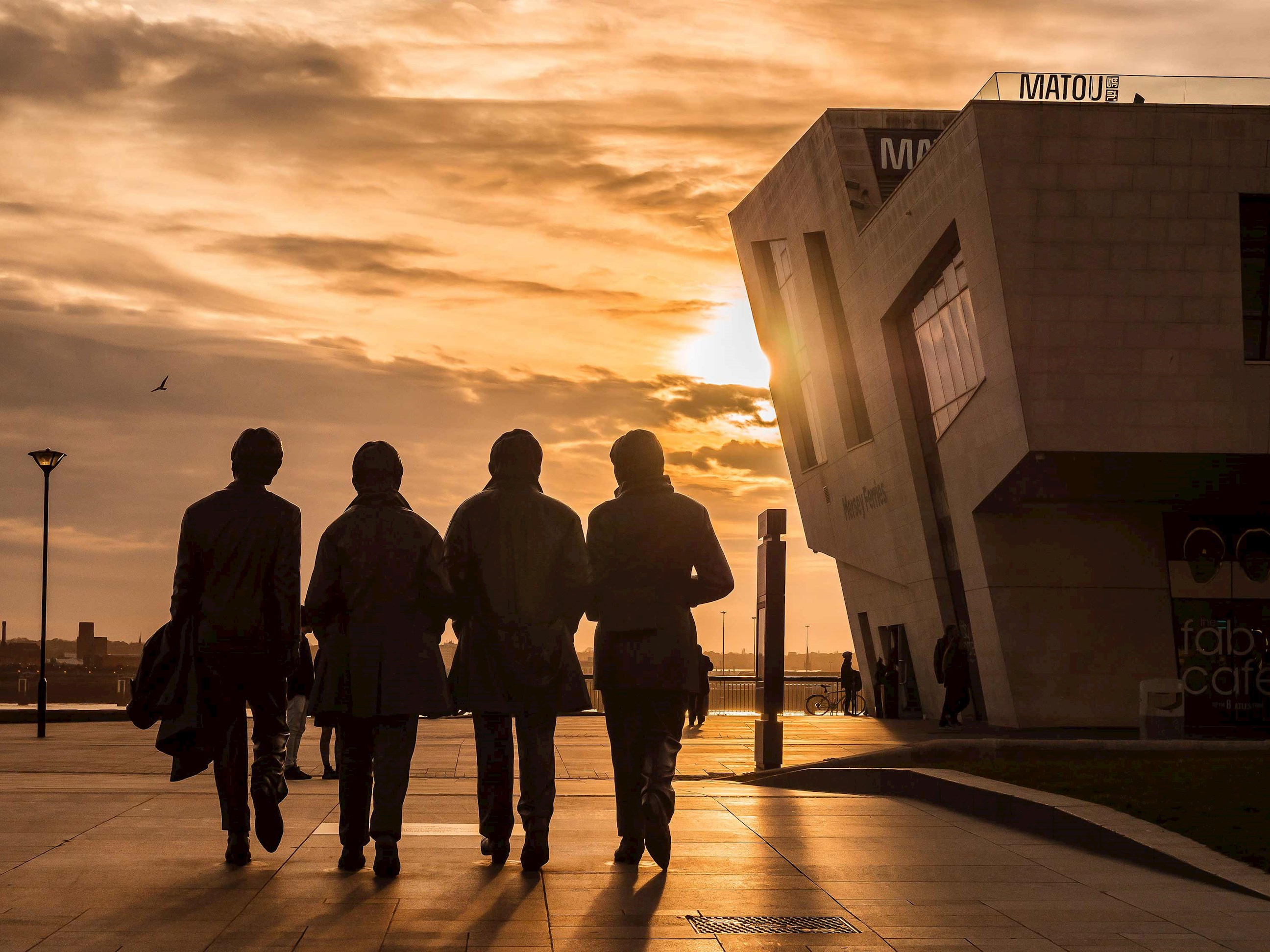 A sunset view of The Beatles Statue in Liverpool, England