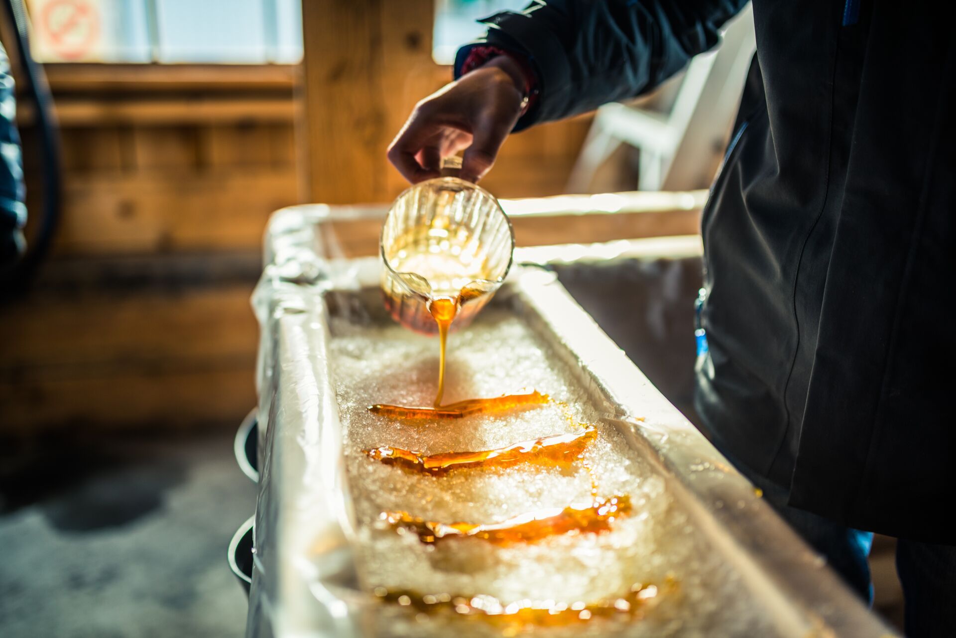 Person pouring Maple Syrup onto snow at Sugar Shack in Canada