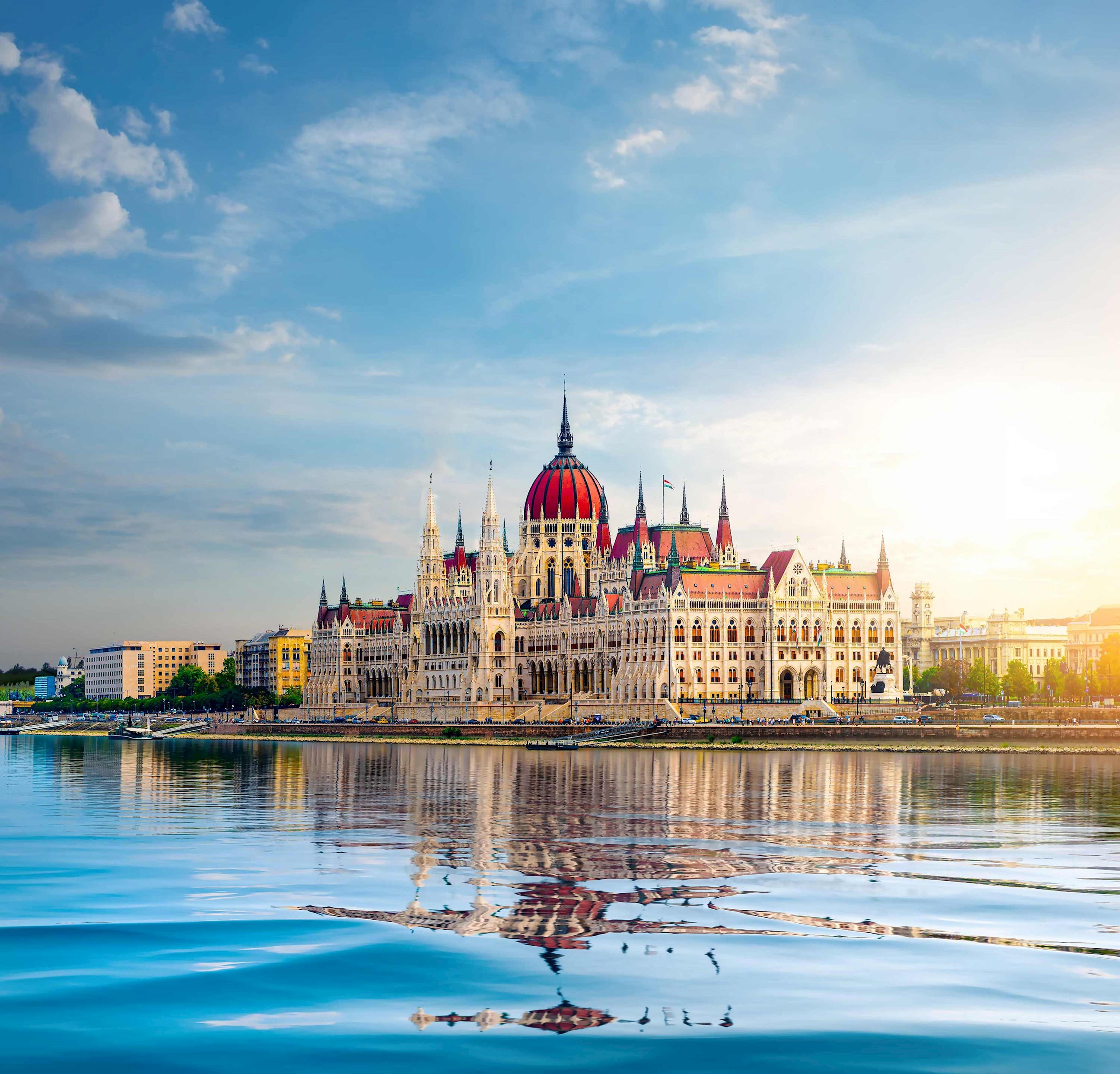 Historic structure with red dome and towers beside a wide river in Budapest, Hungary