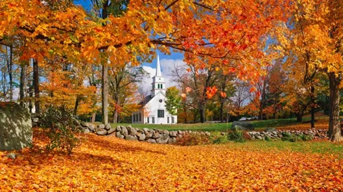 A white church surrounded by fall leaves in New England