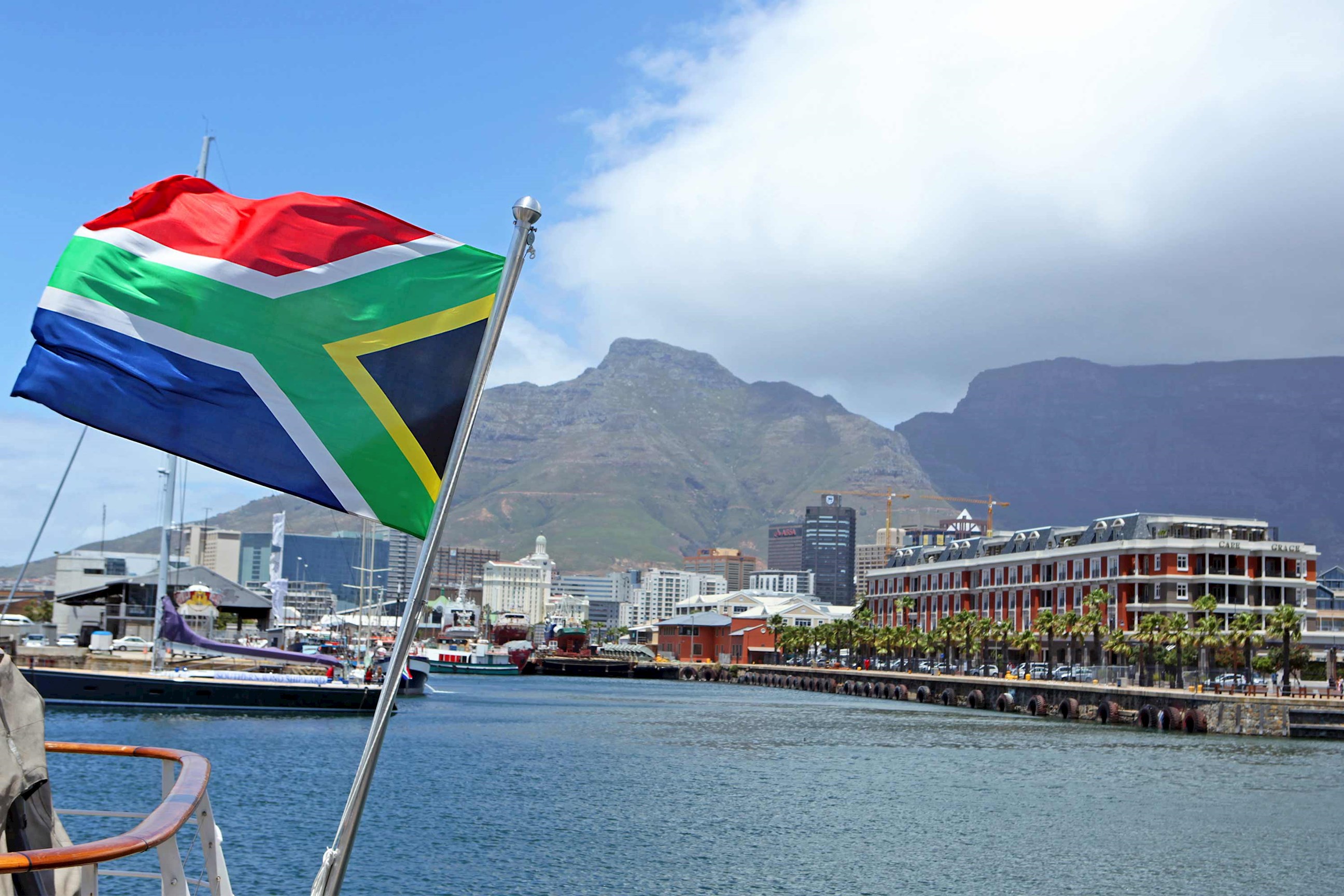 South African flag waving on boat at Cape Town waterfront with Table Mountain