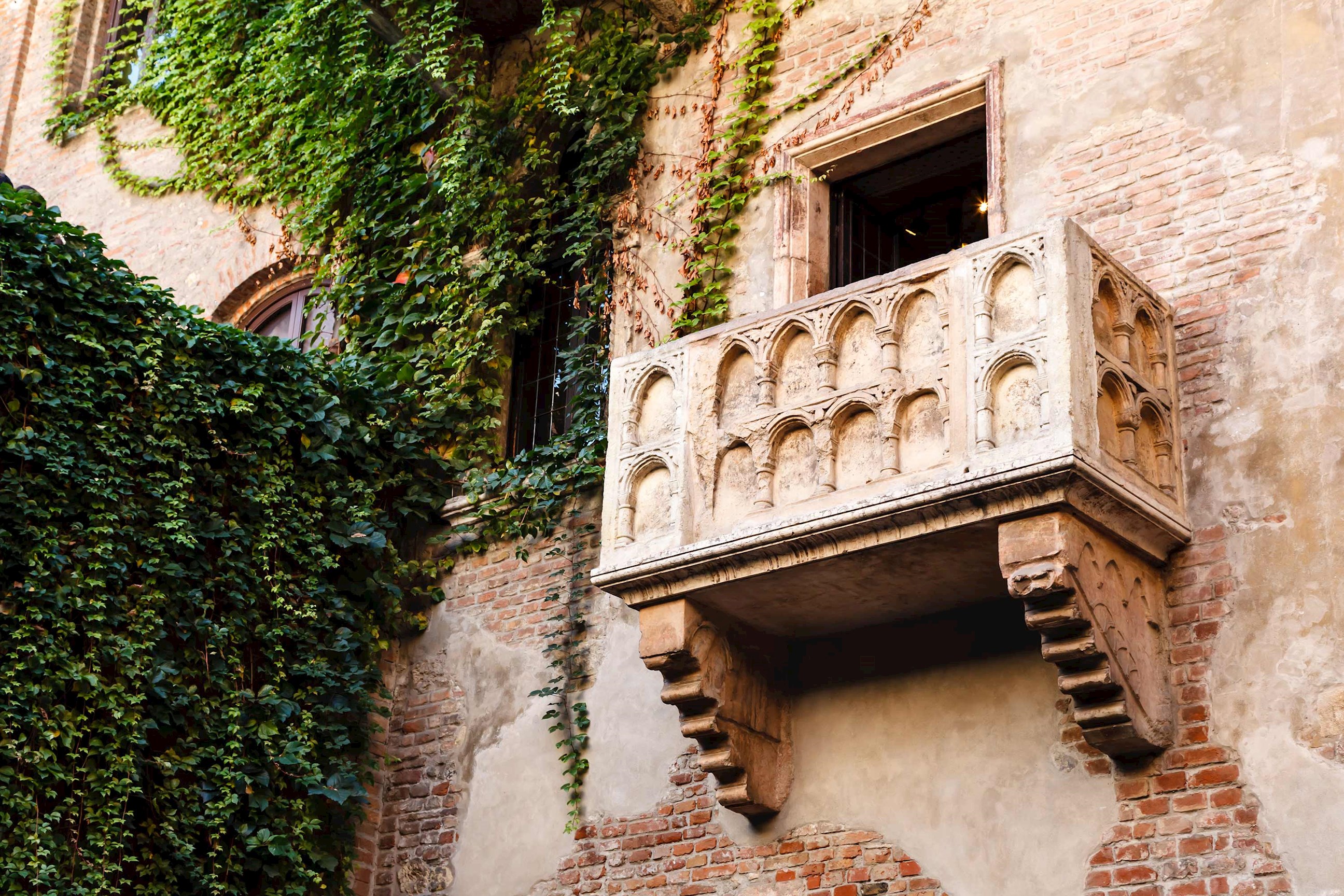 Historic stone balcony on ivy-covered wall of old building in Verona, Italy