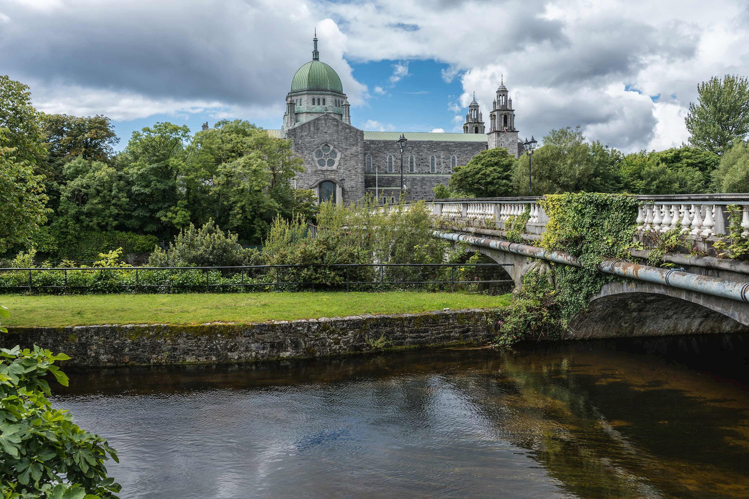 Stone bridge with domed cathedral in background in Galway, Ireland