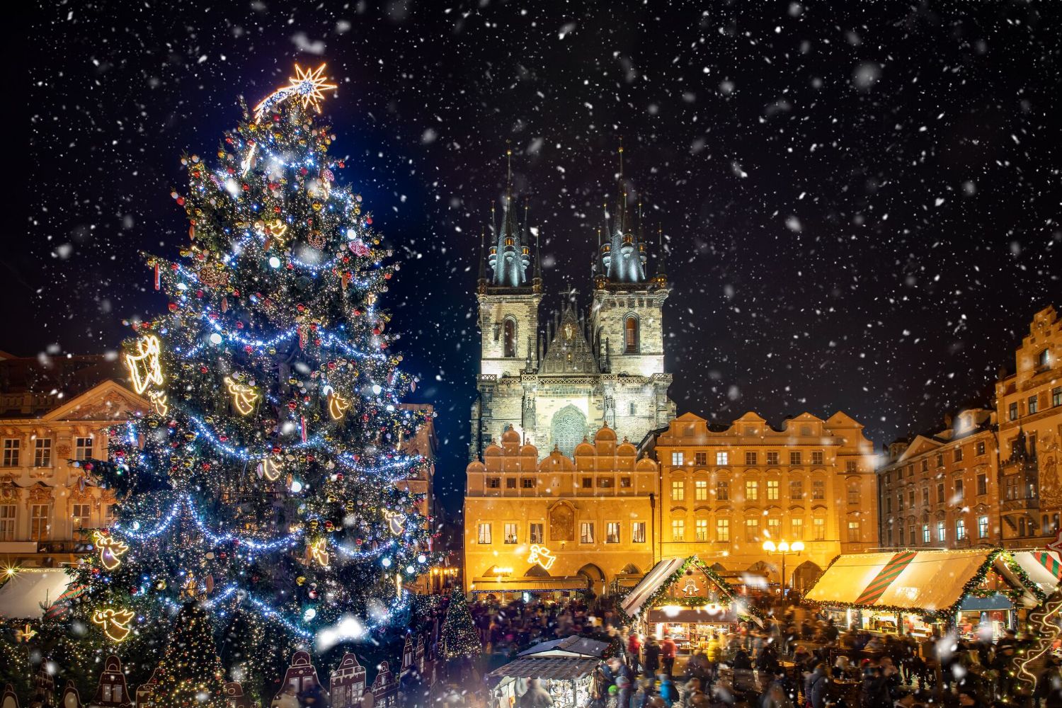 low-angle-view-of-decorated-christmas-tree-and-tyn-church-against-sky-during-snowfall-at-night-1253454232.jpg