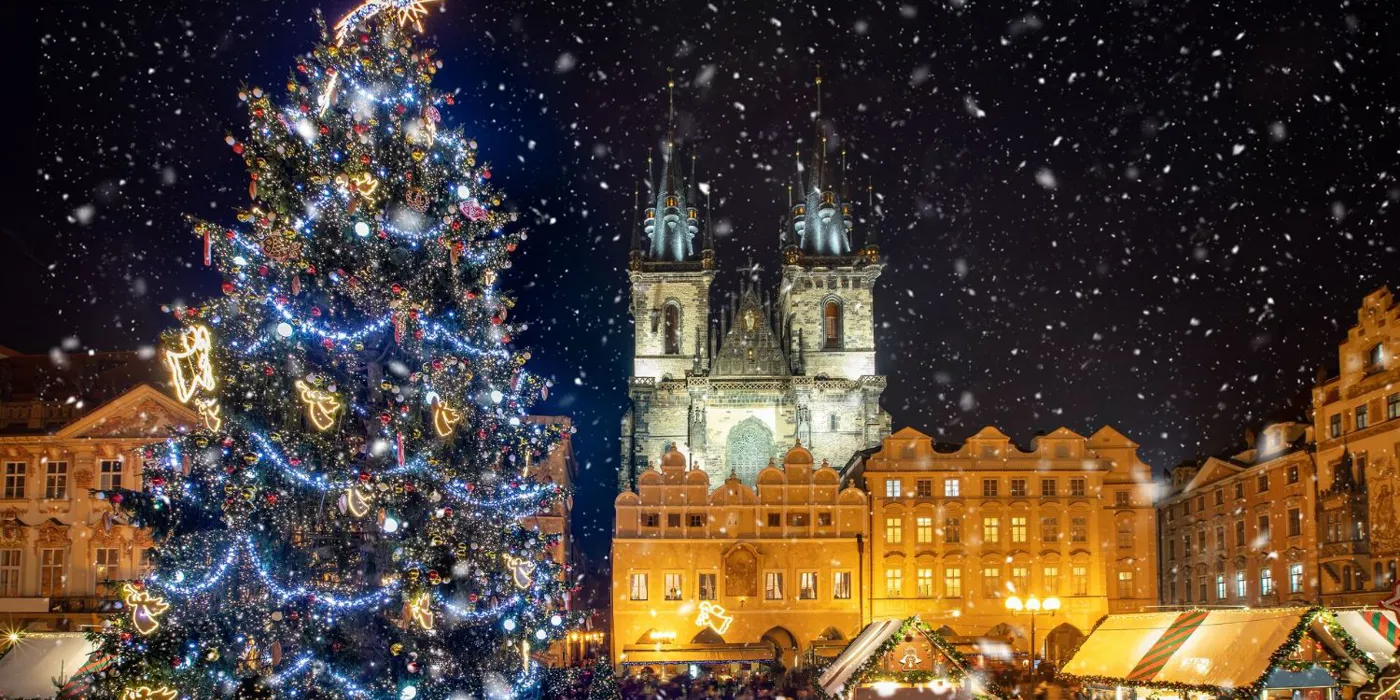 low-angle-view-of-decorated-christmas-tree-and-tyn-church-against-sky-during-snowfall-at-night-1253454232.jpg