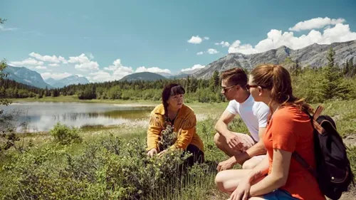 A group of people sitting next to a lake in Canada