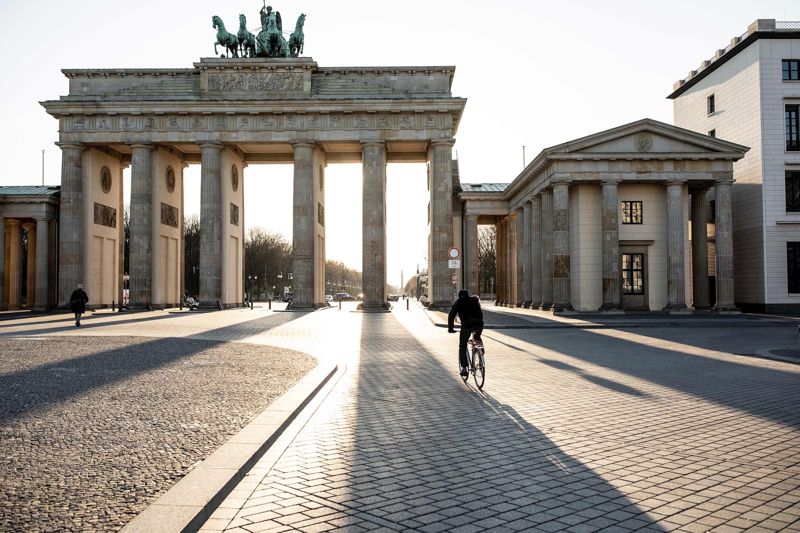 Cyclist riding through a gate in Berlin during golden sunrise in Berlin, Germany