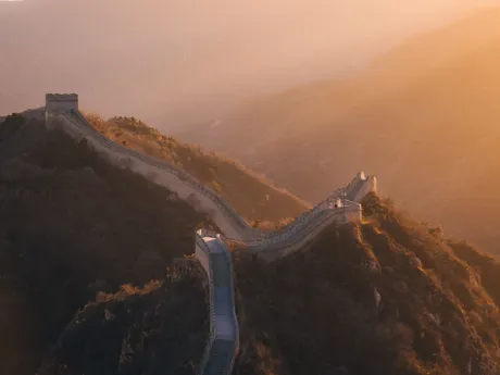 The Great Wall of China snakes over hilltops as the sun sets
