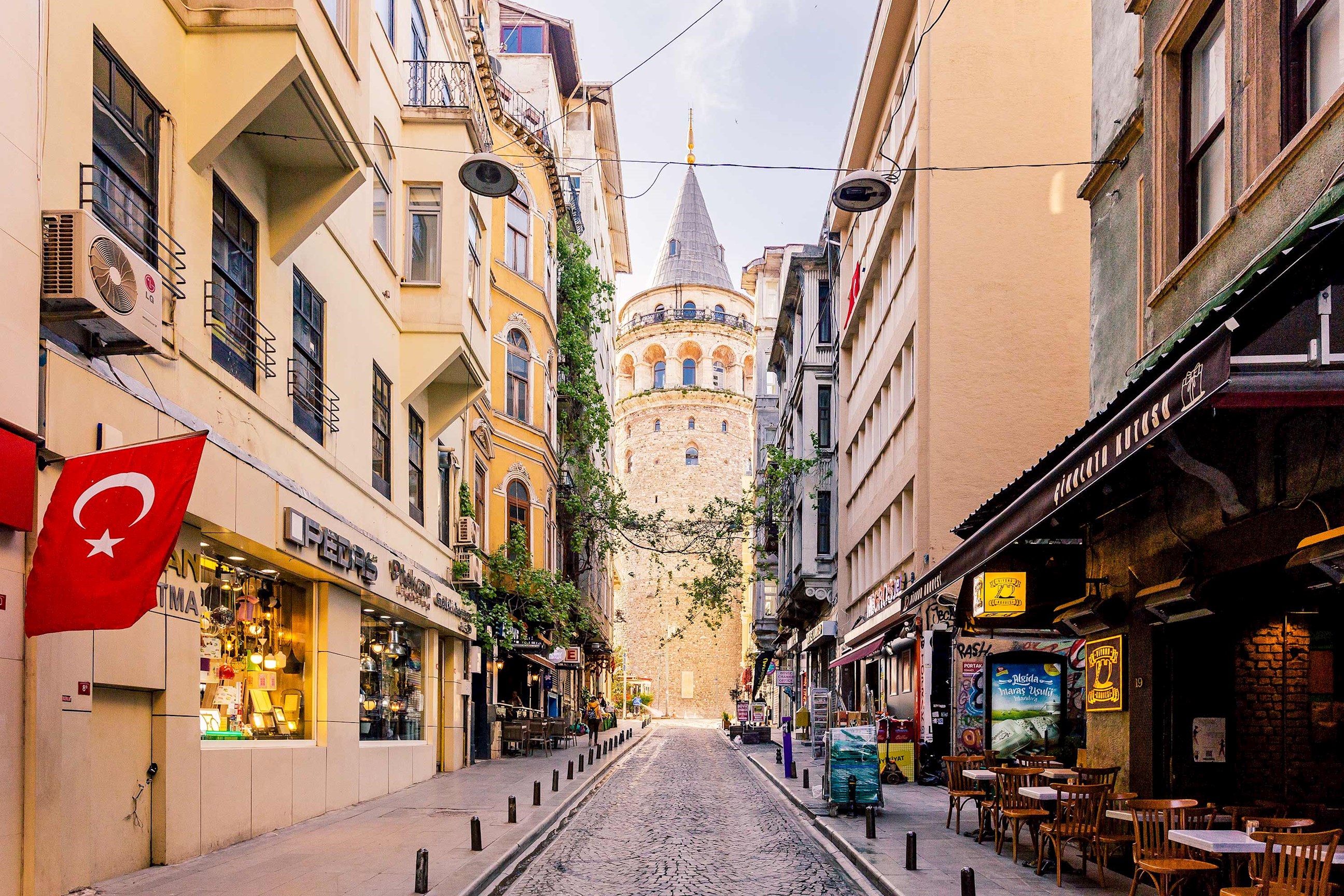 Galata Tower viewed from narrow street lined with shops in Istanbul, Turkey