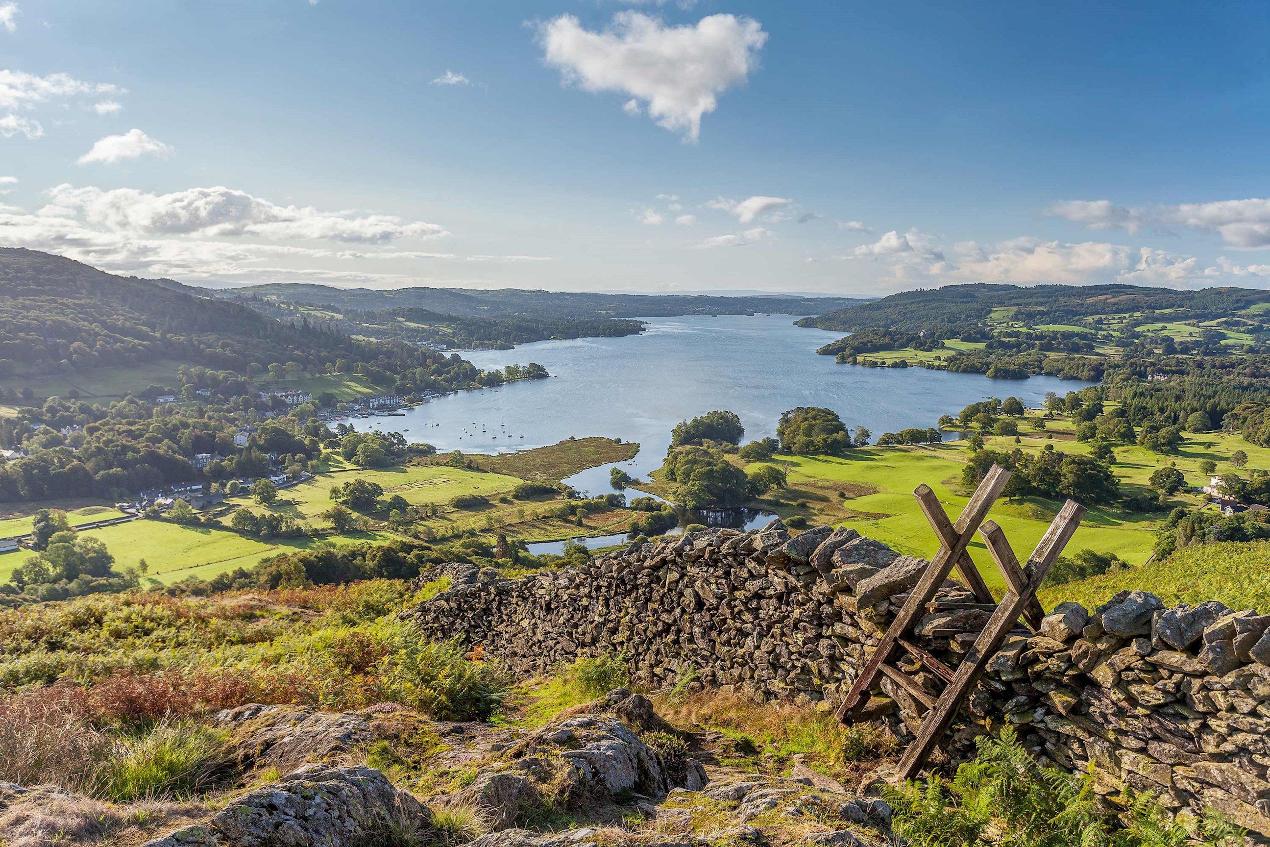 Panoramic view of a lake surrounded by green hills in Lake District, England