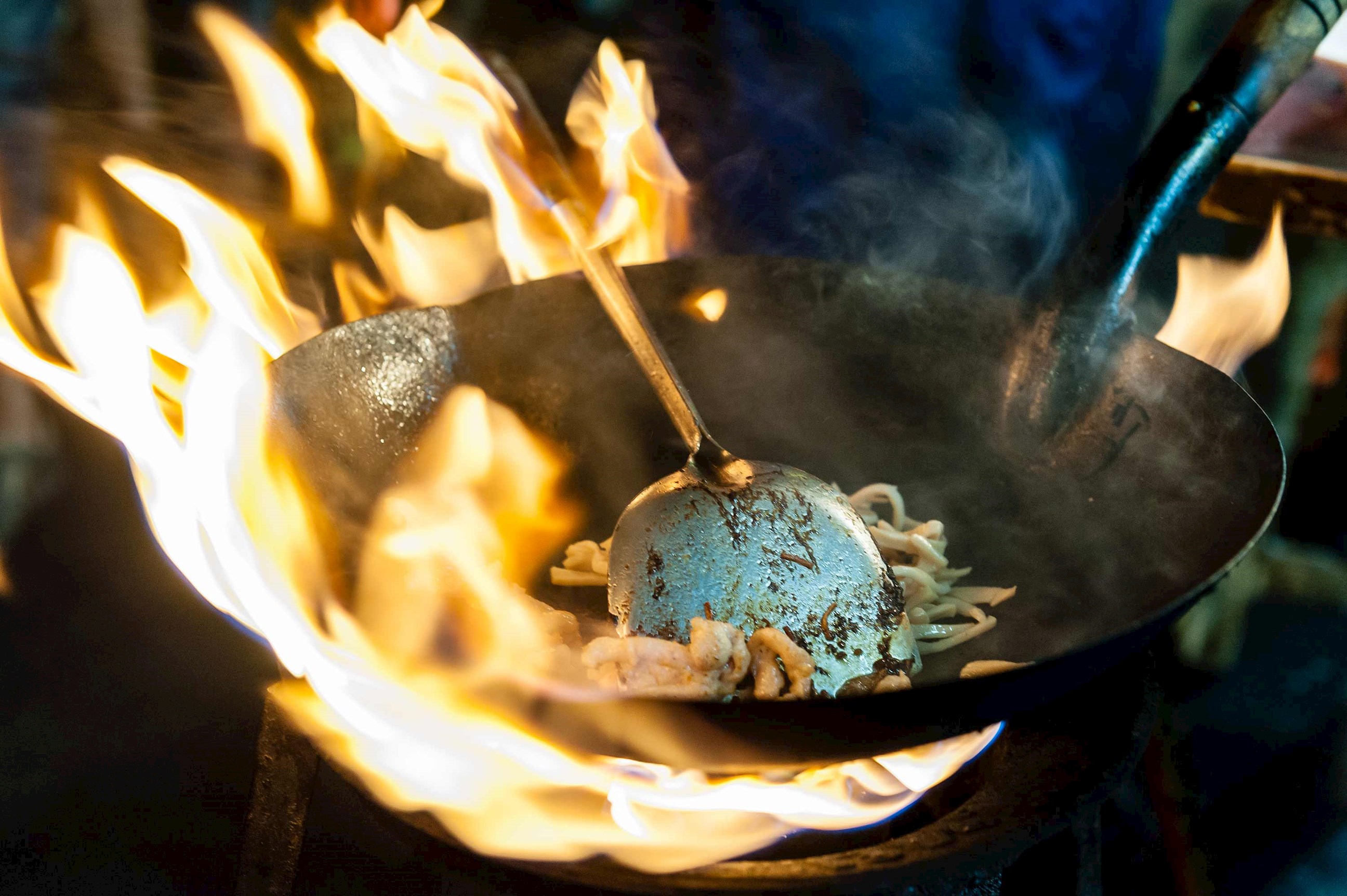 Close-up of wok stir-frying noodles over high flame