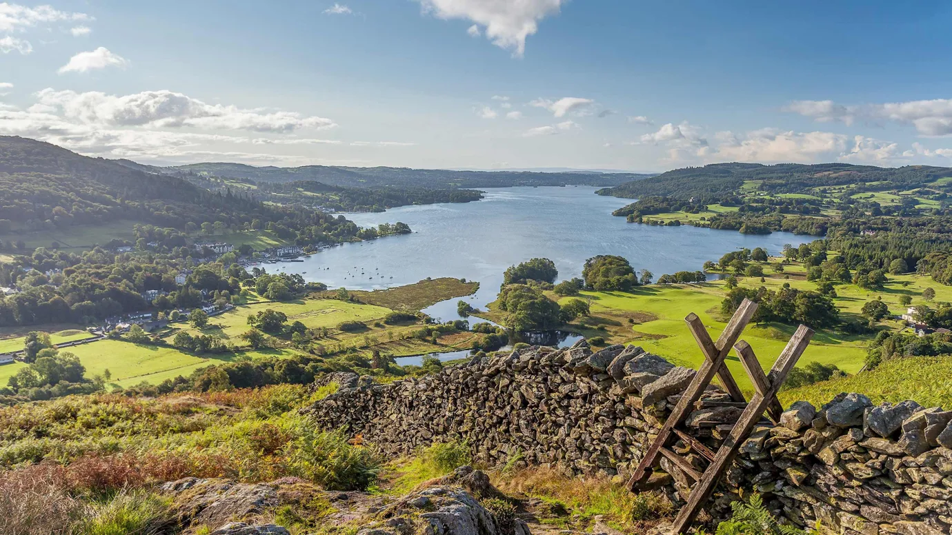 Panoramic view of a lake surrounded by green hills in Lake District, England