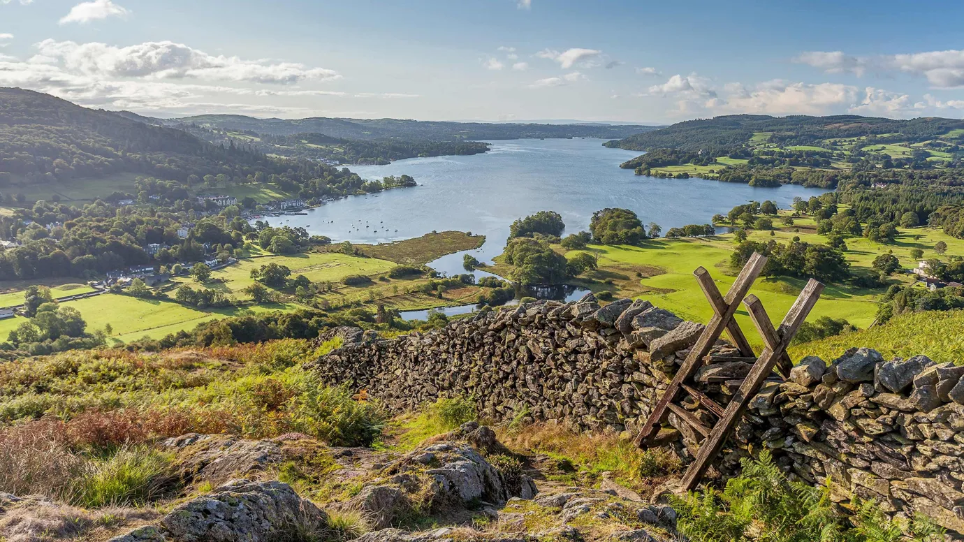 Panoramic view of a lake surrounded by green hills in Lake District, England
