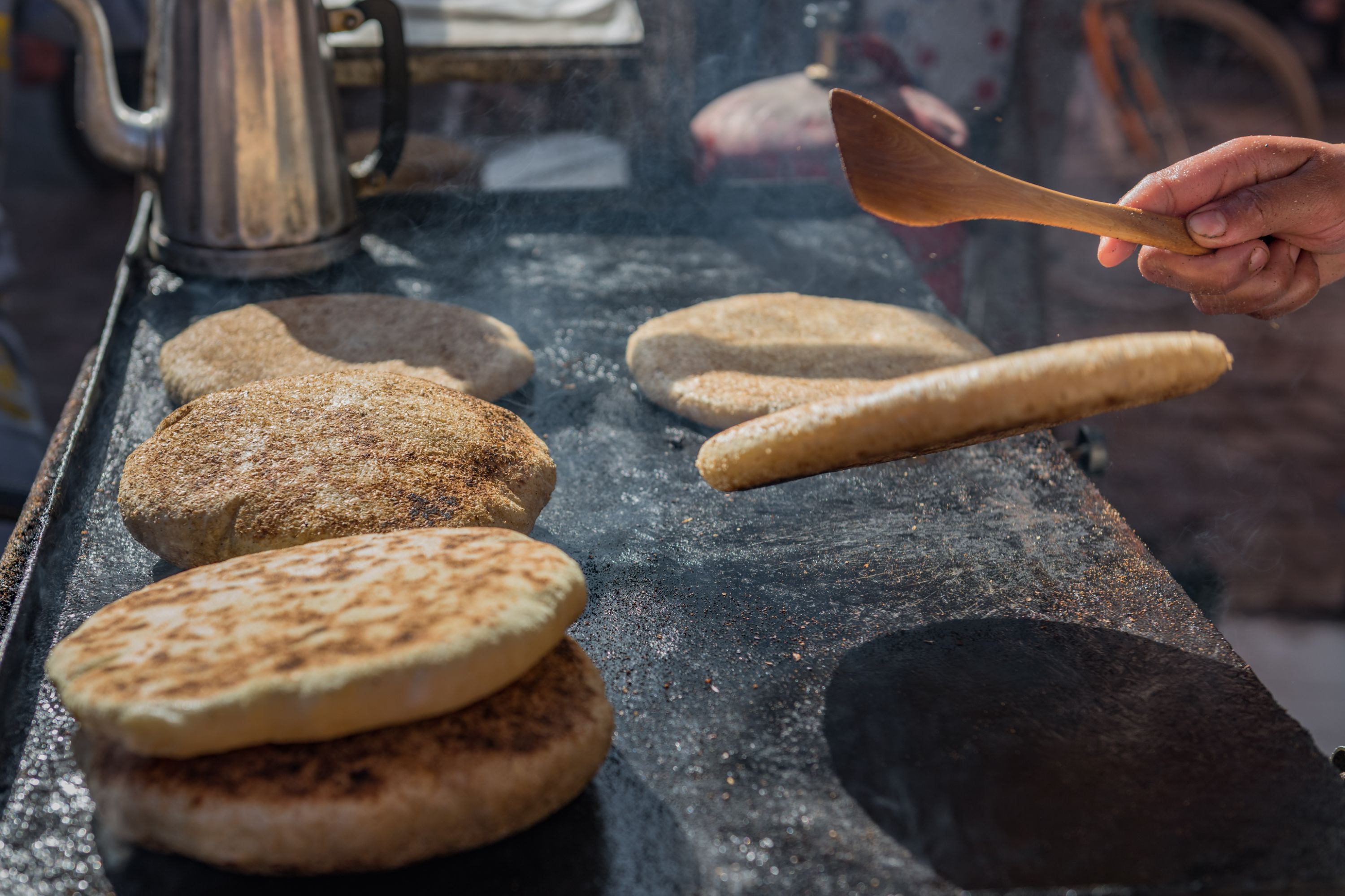 Moroccan flatbreads being cooked and flipped over 
