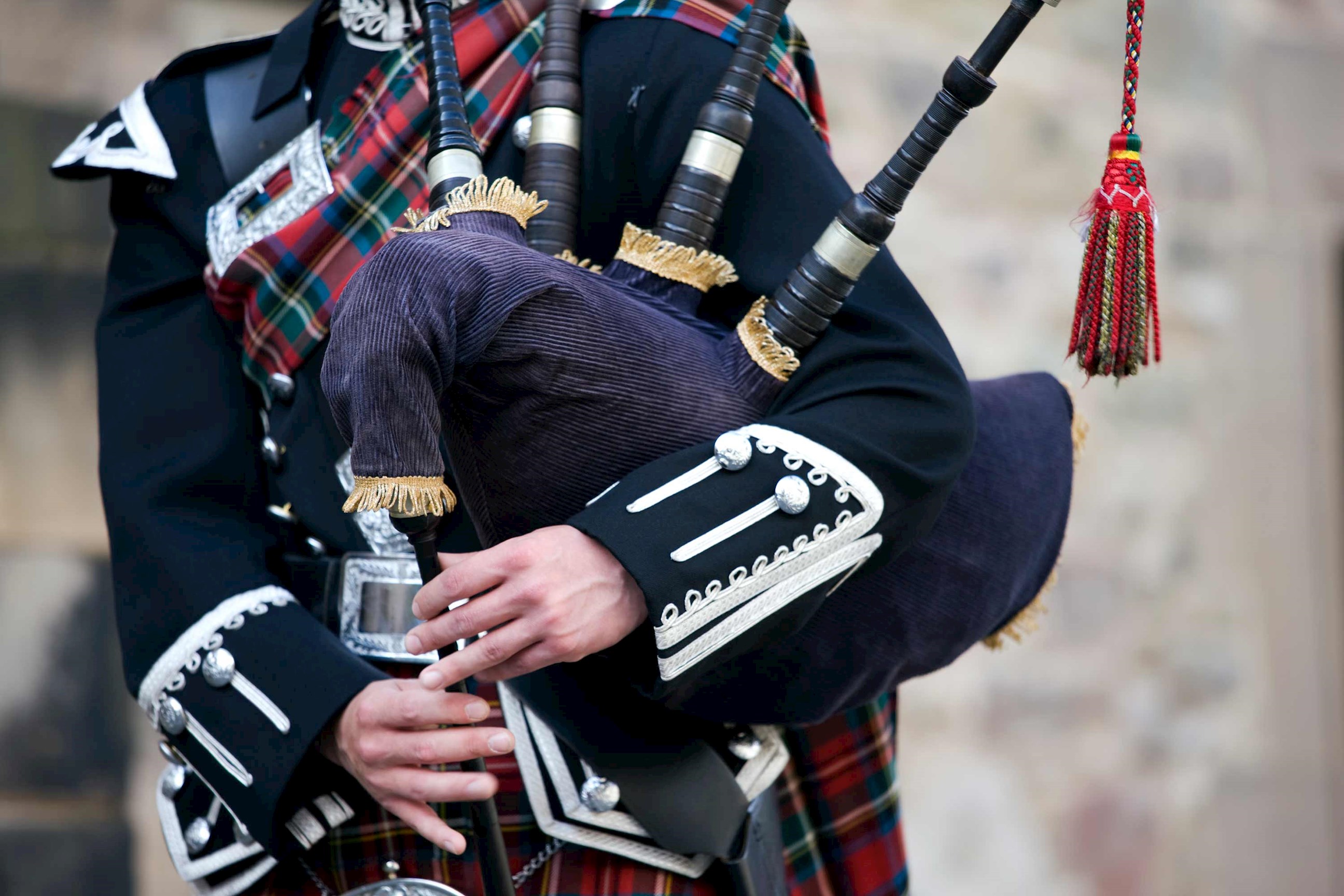 Close-up of person wearing traditional uniform playing bagpipes in Edinburgh, Scotland
