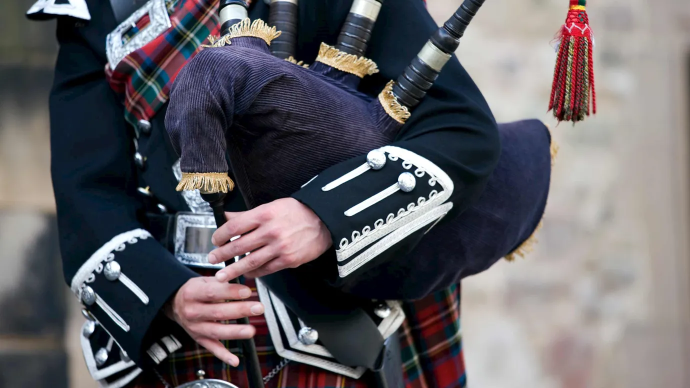 Close-up of person wearing traditional uniform playing bagpipes in Edinburgh, Scotland