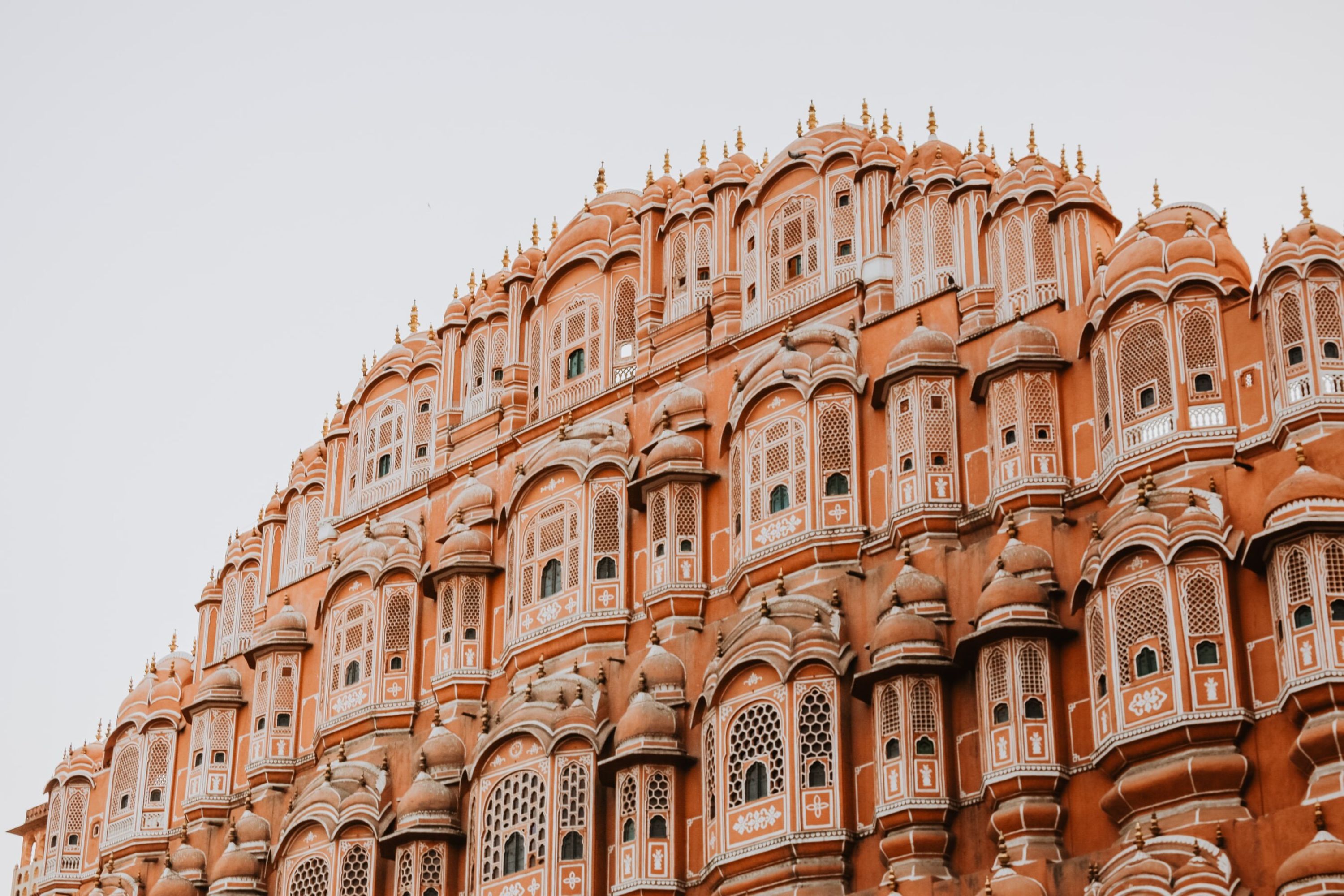 The Palace of Winds in Jaipur, India, built in red stone with many highly decorated windows.