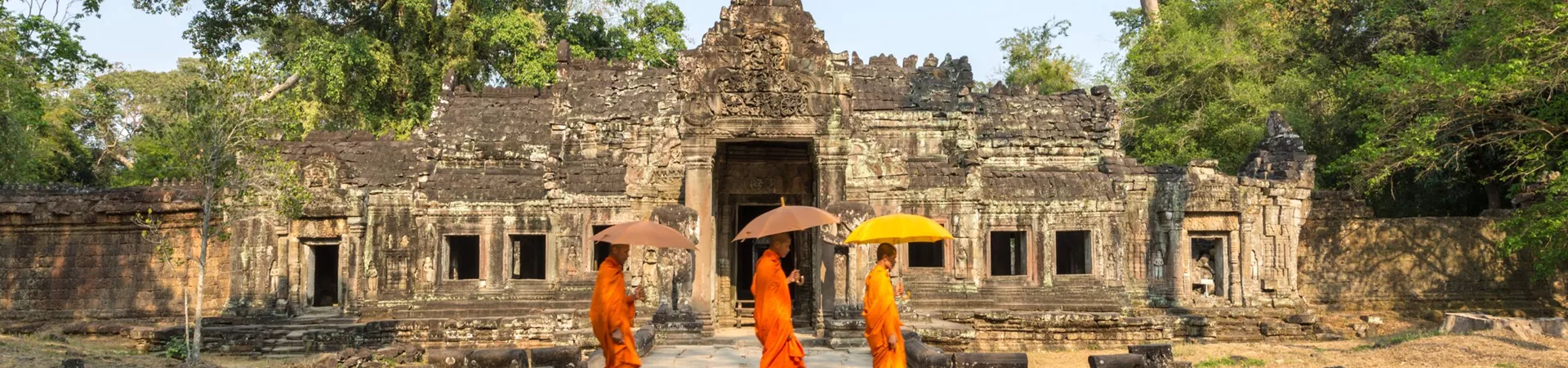 Three Monks With Umbrellas Walking Inside A Temple in Angkor Wat, Cambodia